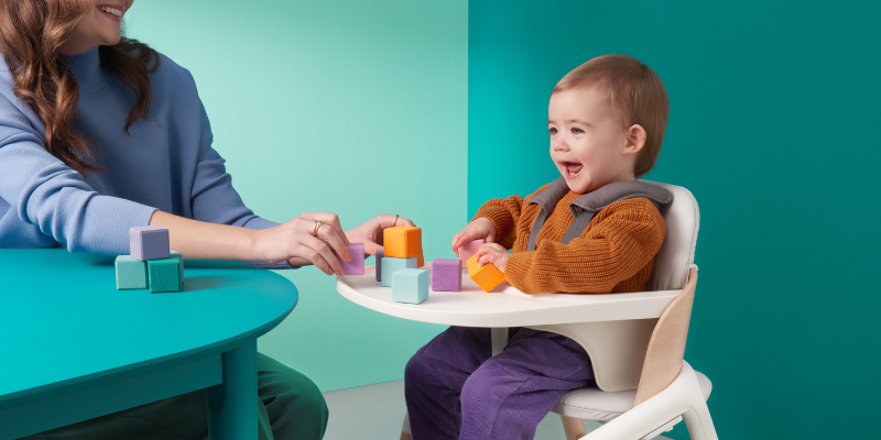 Baby playing with blocks sitting in the Bugaboo Giraffe Complete High Chair