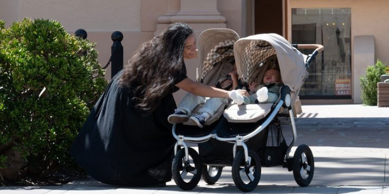 Mom kneeling down and tending to babies in Bumbleride Indie Twin Double Stroller