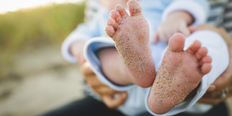 Mom holding up toddlers sandy feet