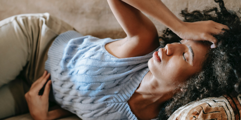 Woman Holding Head While Lying on Couch