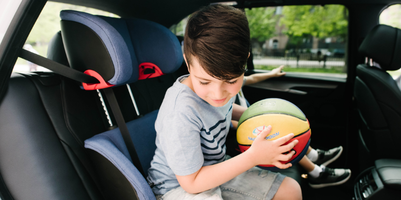 Little Boy Sitting in Clek Oobr Booster Seat Holding A Ball