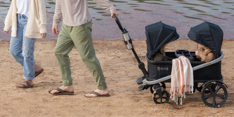 BOB Renegade Wagon on Beach Being Pulled By Man and Woman With Two Children Sitting Inside