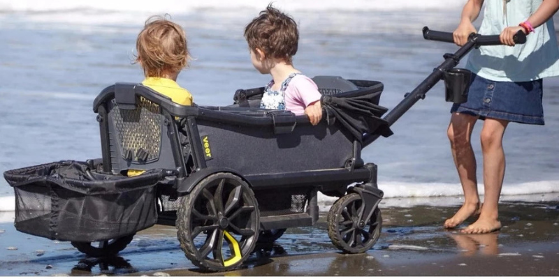 Mom pulling along 2 kids sitting in a veer cruiser