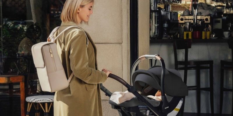 Woman walking with a Romer Juni Infant Car Seat in a travel system