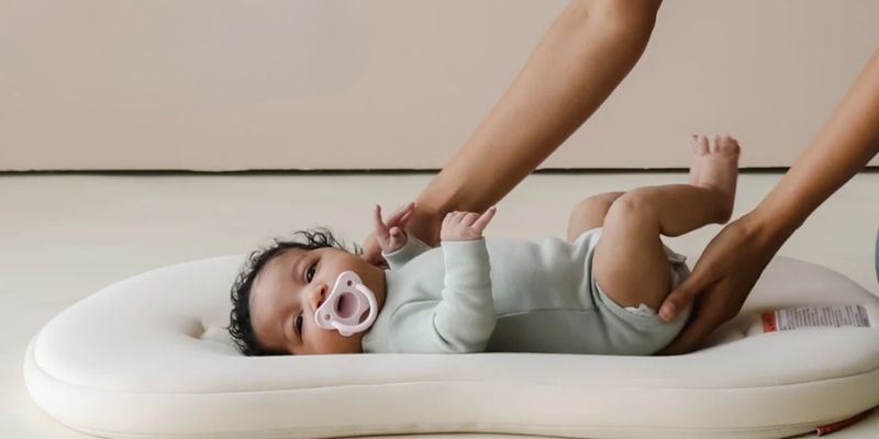 Baby lying in a Snuggle Me Organic Infant Lounger Curve