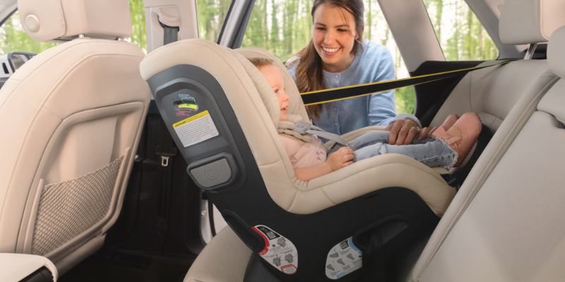 Mom smiling at toddler sitting in the back seat of car in UPPAbaby Rove Convertible Car Seat