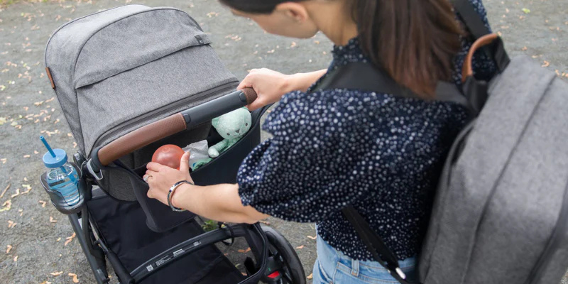 Mom putting water bottle in carry-all storage stroller carrier