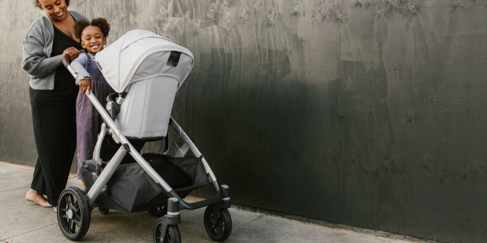 Mom pushing UPPAbaby VISTA V2 with Toddler standing on kick board