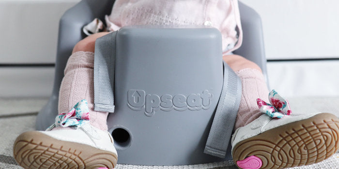 Baby girl sitting in an upseat booster seat