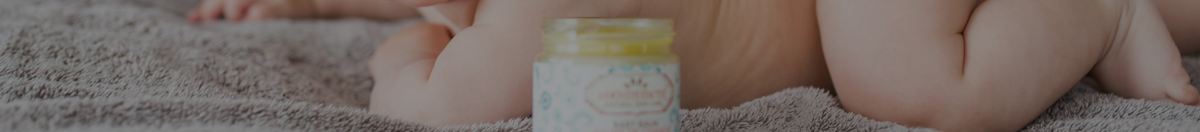Baby laying on a blanket with Anointment baby balm in front of him