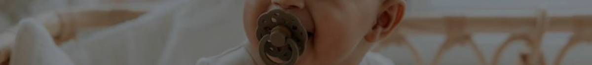 Little baby in a bassinet with a BIBS pacifier