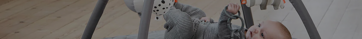 Little baby playing in a Done By Deer activity gym during tummy time