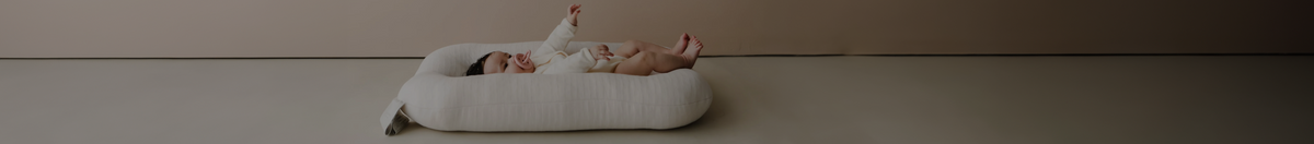 Baby lounging in a white Snuggle Me organic lounger