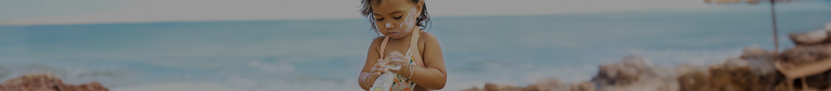 Little girl applying Sun Bum suncreen on her face on the beach