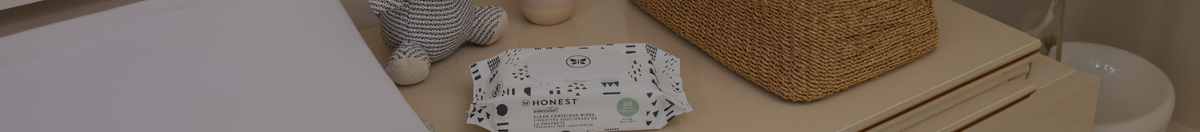 A pack of The Honest Company diaper wipes sitting on a nursery dresser beside change pad