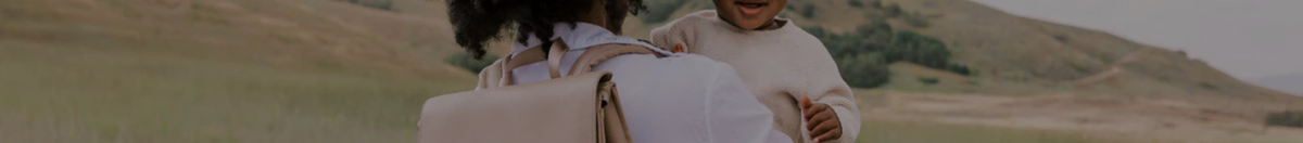 Mother carrying baby with a Freshly Pick backpack style diaper bag in beige