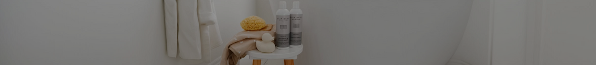 Baja baby shampoo and conditioner sitting on a stool with a white rubber ducky beside a bath tub