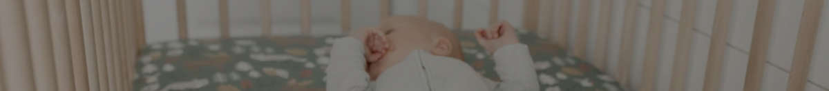 Baby sleeping in a crib with a Copper Pearl crib sheet