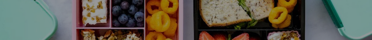 Two bento boxes filled up with a sandwich, snacks, fruit and vegetables, perfect for lunchtime. 