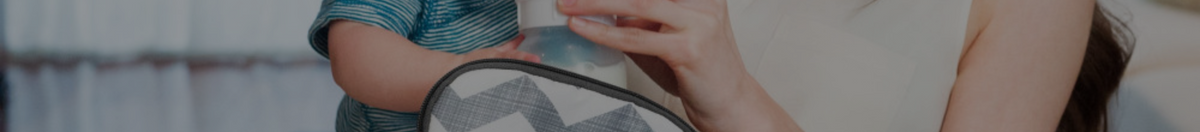 Mother holding baby while putting a baby bottle into a bottle cooler bag