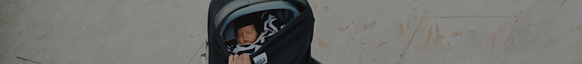 Baby sleeping in UPPAbaby MESA infant seat covered in an Over Company Black Car Seat Cover