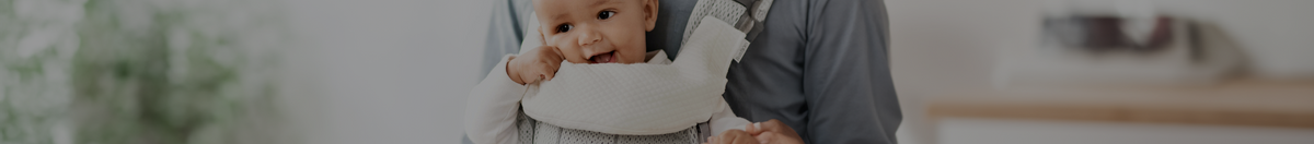 Father carrying baby in a Babybjorn baby carrier with a Teething Pad & bib attached