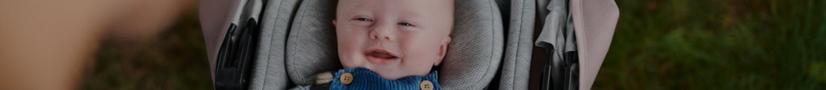 Little baby smiling in an UPPAbaby VISTA V2 stroller snuggly in their stroller insert.