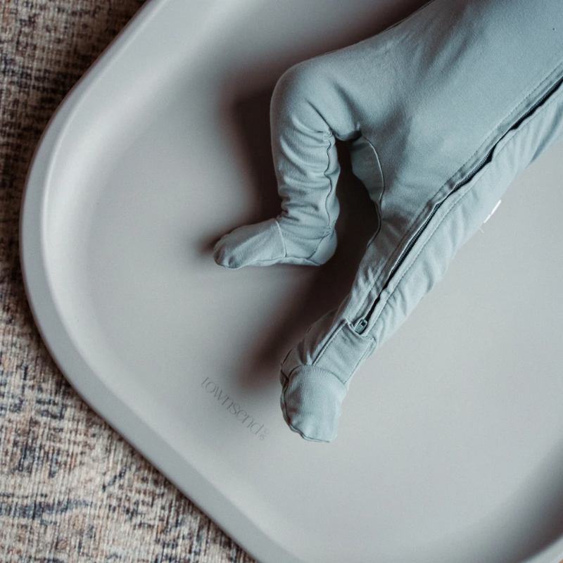 Baby lying on Townsend Avenue wipeable changing pad during diaper change in wheat
